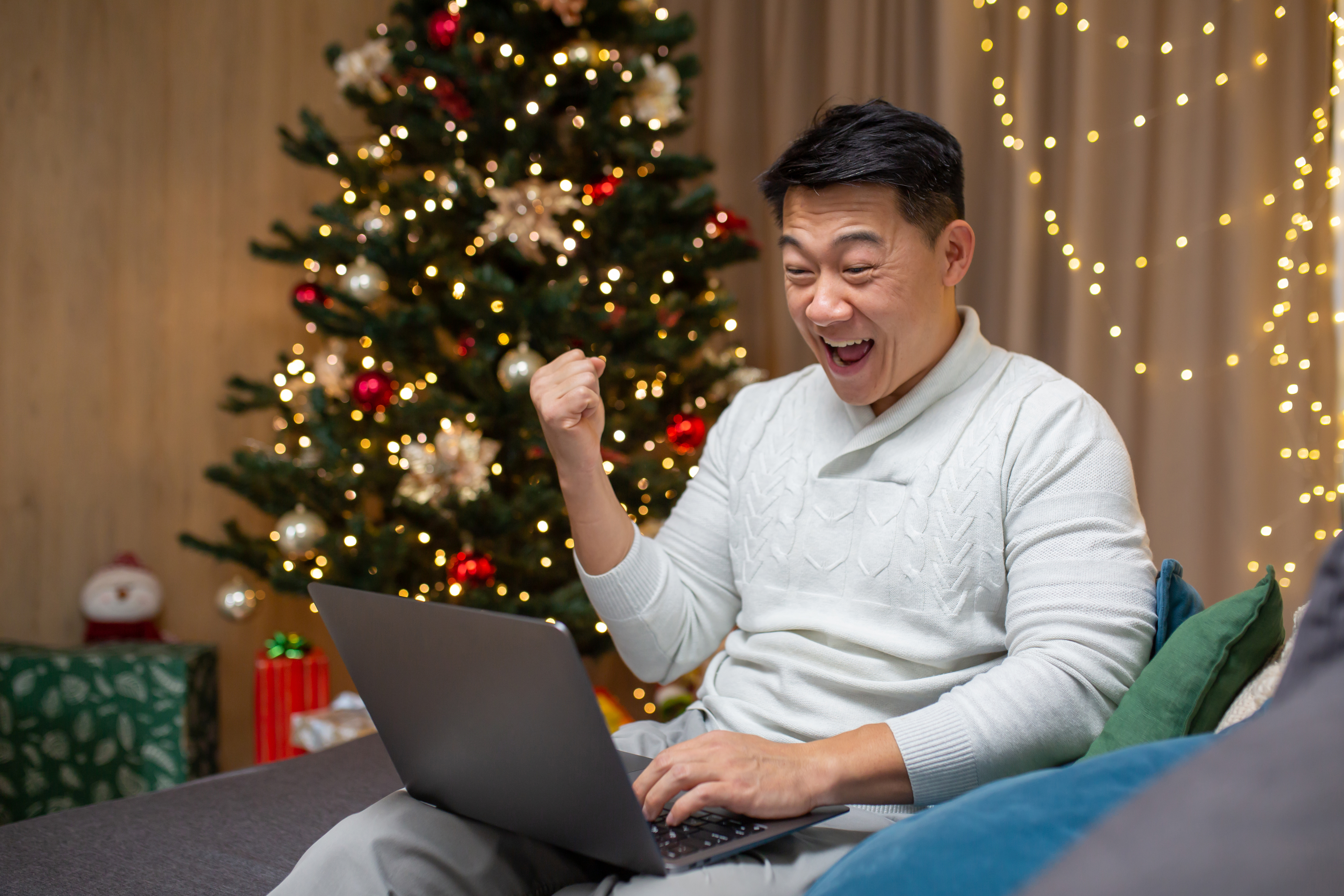 Man celebrating new year at home and christmas, asian got good news online reading from laptop and